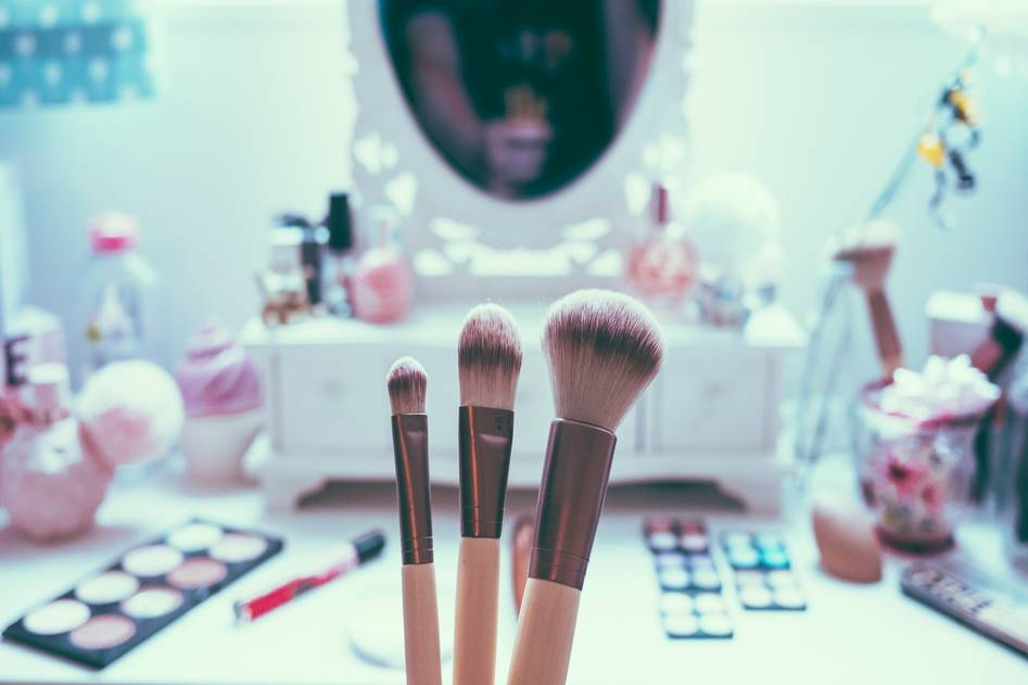 Professional makeup artists competing on stage with dramatic lighting and vibrant cosmetics