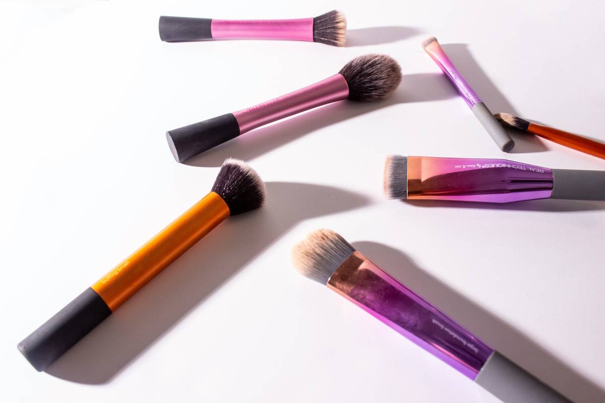 Close-up of a professional makeup show brush with synthetic bristles and matte black handle used in a competition setting